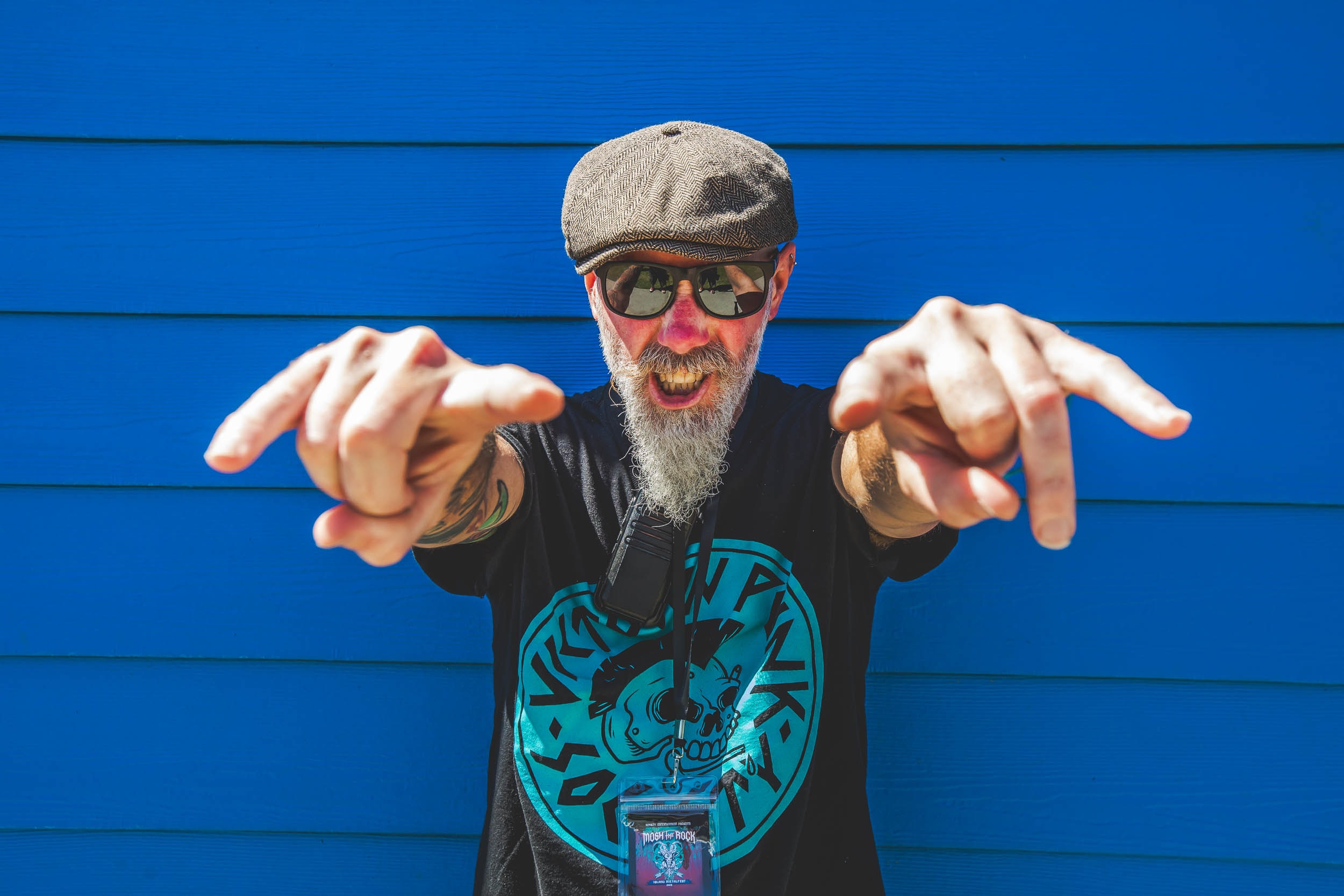 Festival-goer pointing at the camera against a blue wall at Mosh the Rock