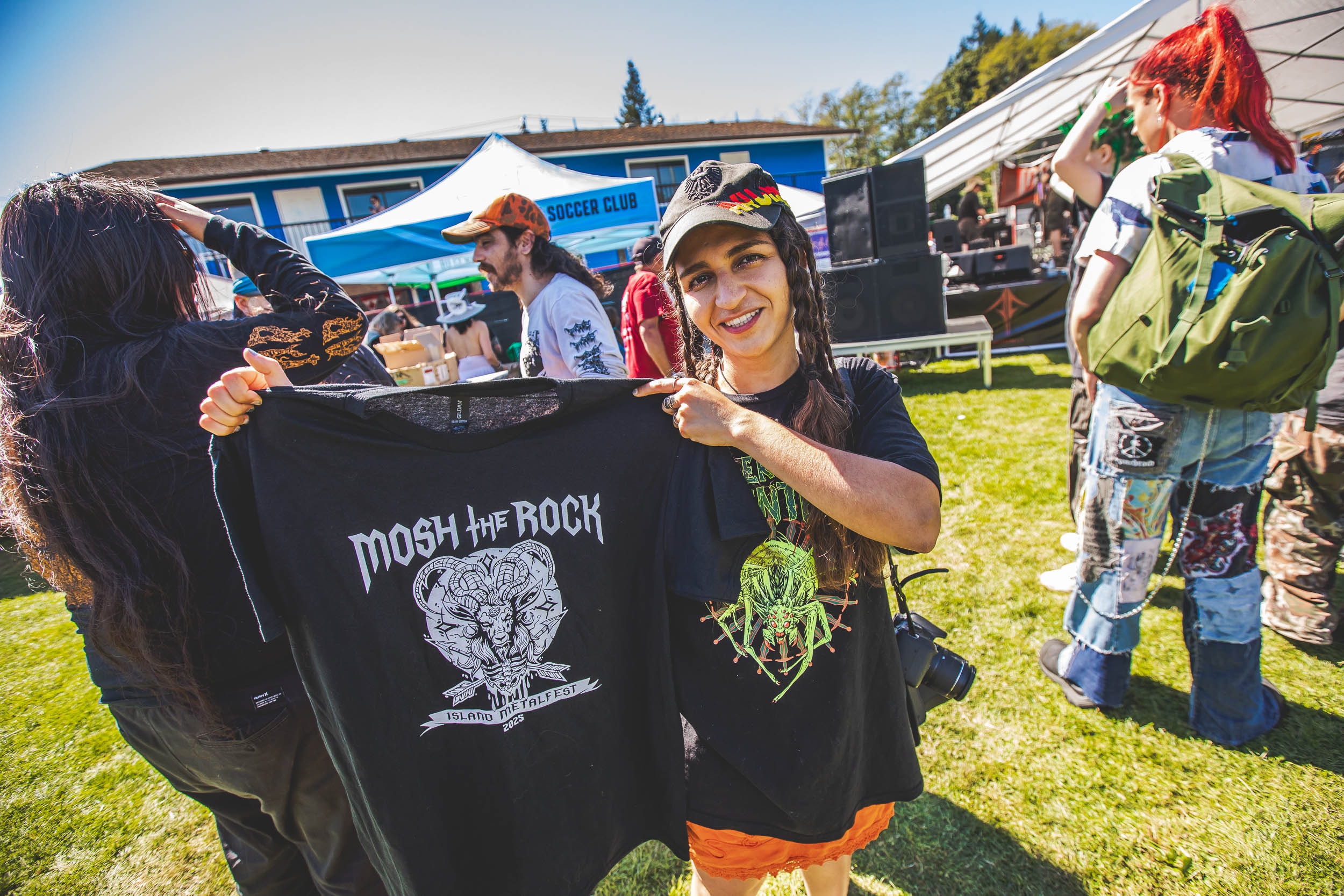 Fan holding up a Mosh the Rock t-shirt at the merch table