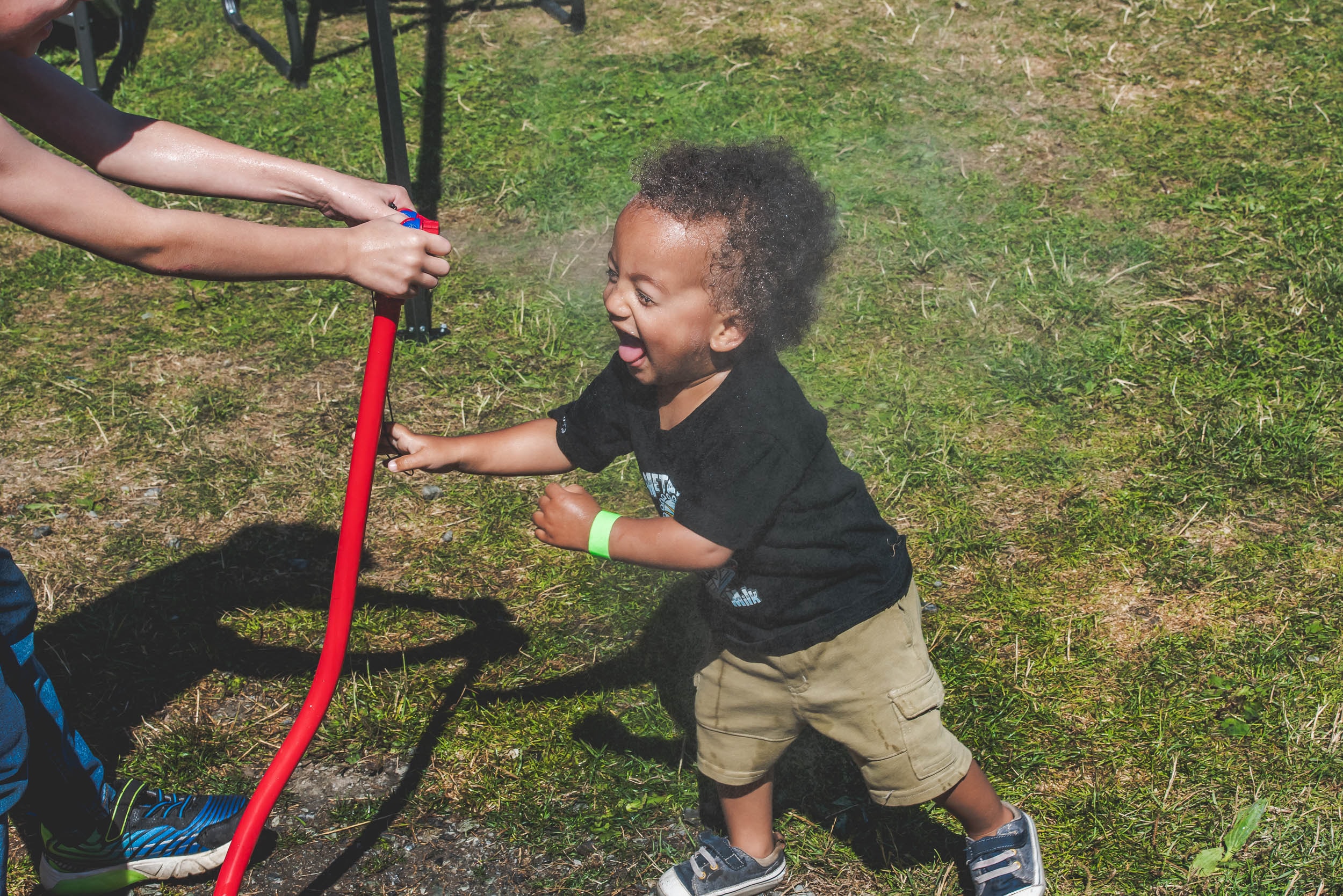 Young festival-goer playing with a water hose at the grounds